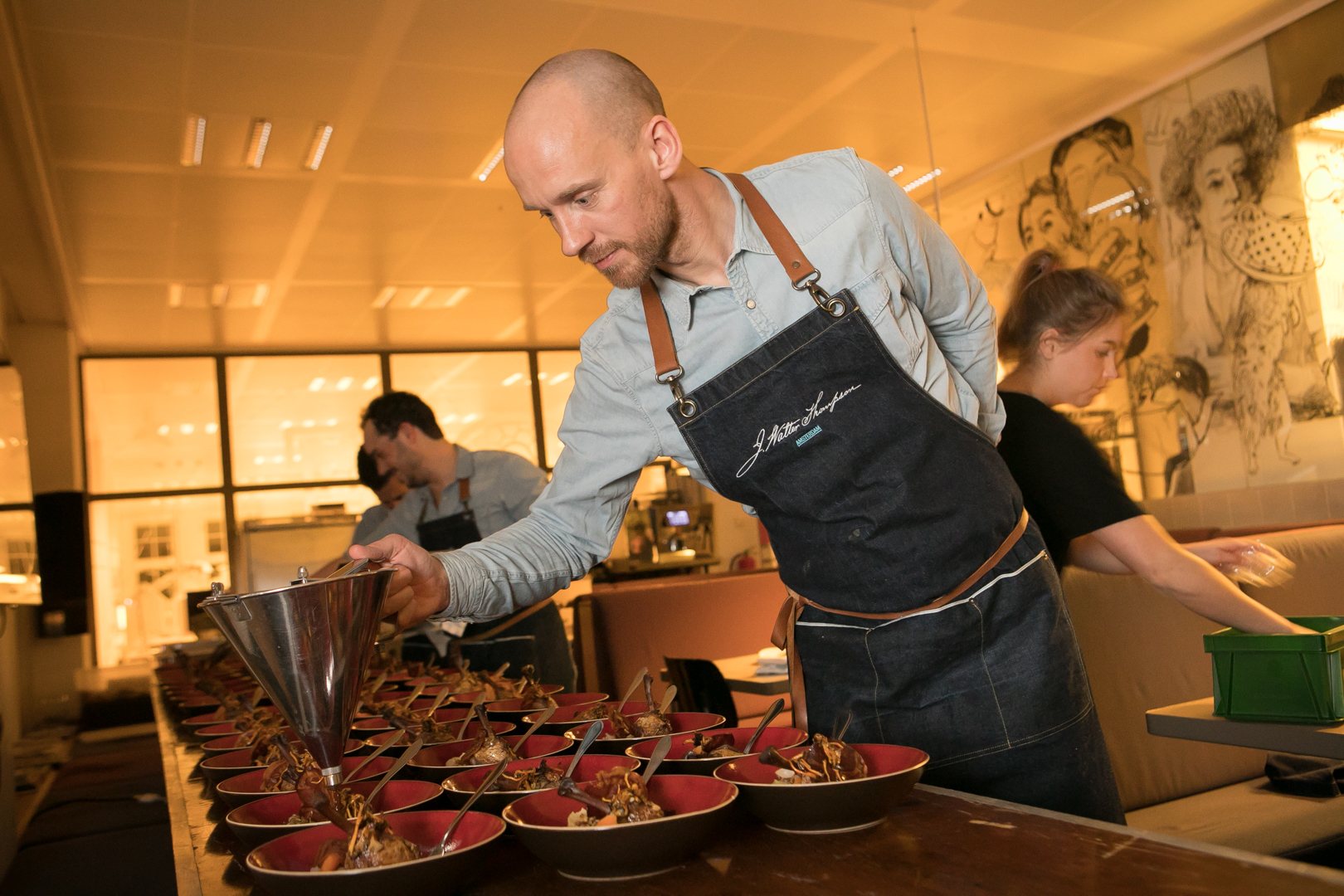 Een kok richt borden op een lange tafel